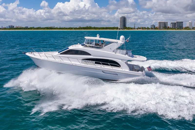 Starka Yacht Photos Pics 2009 Hatteras 64 Motor Yacht cruising on blue ocean near city skyline.