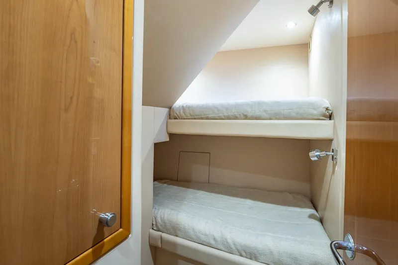 Starka Yacht Photos Pics Bunk beds in 2009 Hatteras 64 Motor Yacht cabin, featuring wooden finishes and cozy lighting.