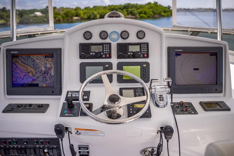 Starka Yacht Photos Pics Control panel of a 2009 Hatteras 64 Motor Yacht with navigation screens and steering wheel.