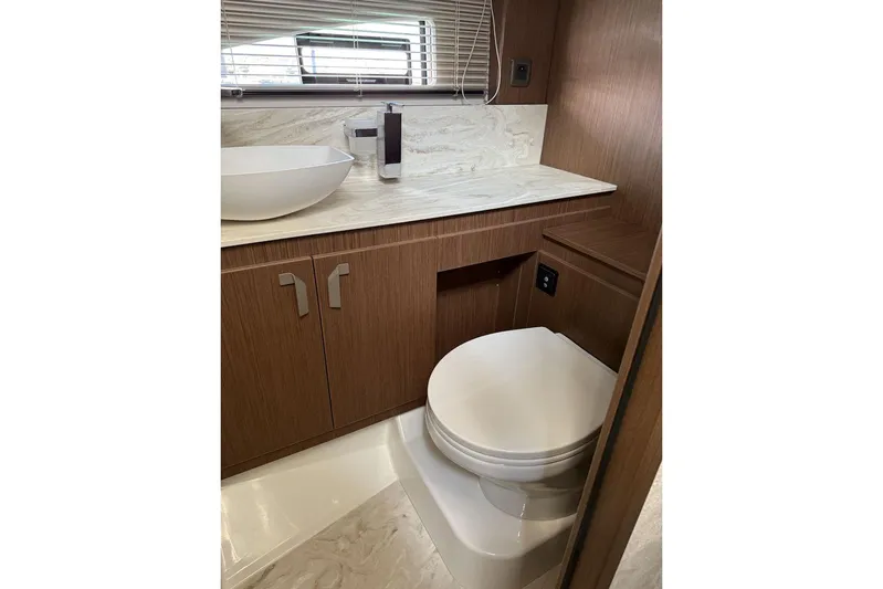  Yacht Photos Pics Modern yacht bathroom with wooden cabinetry, vessel sink, and toilet in Prestige F4.9, 2025 model.