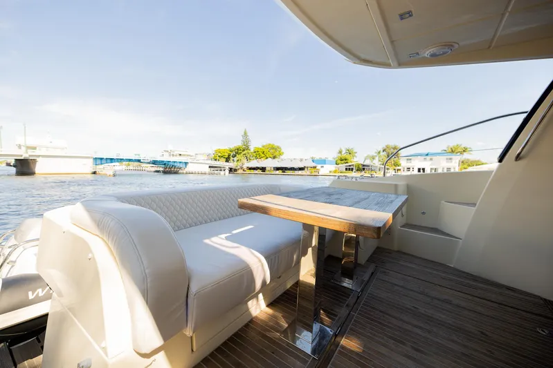 Giada Maria Yacht Photos Pics 2016 Beneteau Monte Carlo 5 yacht deck with seating and table, overlooking a serene waterfront.