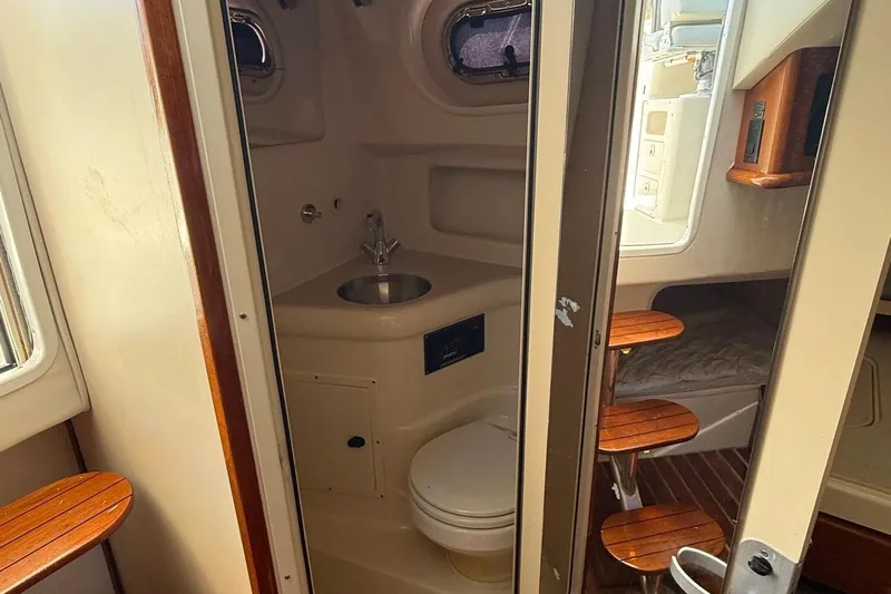  Yacht Photos Pics 2007 Pursuit OS 335 Offshore boat interior with compact bathroom and wooden steps.