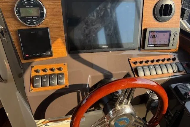 Evangaline Yacht Photos Pics 2022 Ranger Tugs R-25 helm with navigation controls and wooden steering wheel.