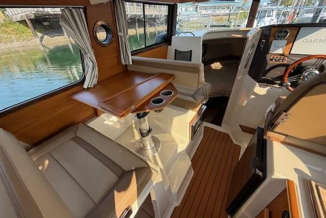Evangaline Yacht Photos Pics 2022 Ranger Tugs R-25 interior with wood accents and seating, featuring a compact dining area.