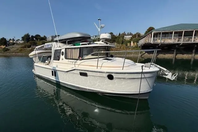 Evangaline Yacht Photos Pics 2022 Ranger Tugs R-25 boat docked on calm water near a wooden pier.