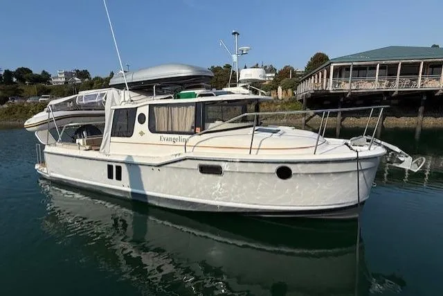 Evangaline Yacht Photos Pics 2022 Ranger Tugs R-25 boat docked in calm waters near a waterfront building.