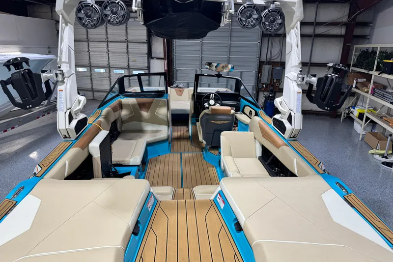  Yacht Photos Pics 2023 Nautique Super Air Nautique S23 interior with beige seating and blue accents in a garage.