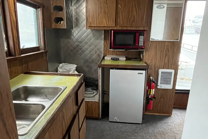 Mi Lana Yacht Photos Pics 1973 Little Hoquiam fishing vessel kitchen with sink, microwave, mini-fridge, and wooden cabinets.