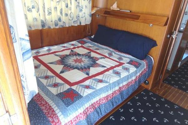 Cozy cabin bedroom in 1985 Pearson 43 Trawler with nautical-themed quilt and decor.