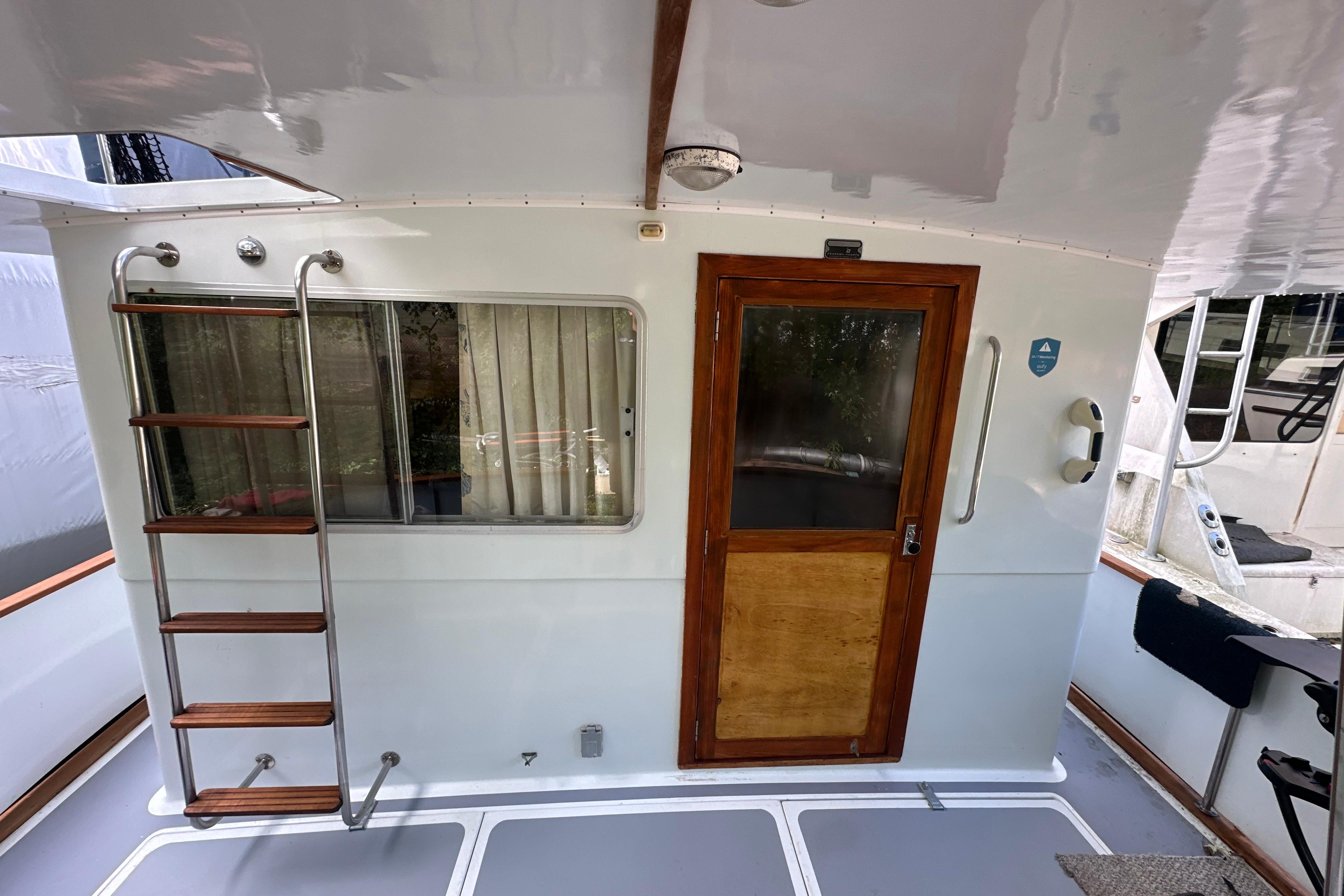 1985 Pearson 43 Trawler aft deck with ladder, window, and wooden door.