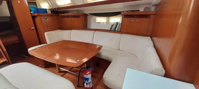 Kaskara Yacht Photos Pics Interior of 2007 Beneteau Oceanis Clipper 523 yacht with wooden table and white seating.