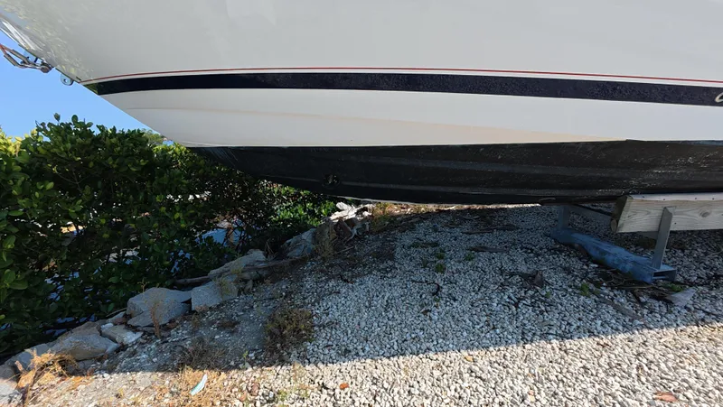 Johnny Be Good Yacht Photos Pics 2012 Intrepid 327 CC boat hull on gravel, partially shaded by greenery.