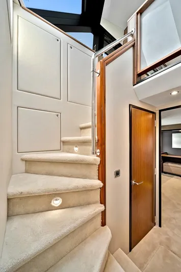 West Yacht Photos Pics Interior staircase of 2017 Hatteras 60 Motor Yacht with carpeted steps and wooden accents.