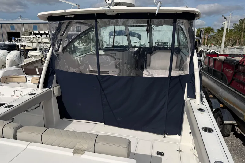  Yacht Photos Pics 2023 Pursuit DC 295 Dual Console boat with protective cover in marina setting.