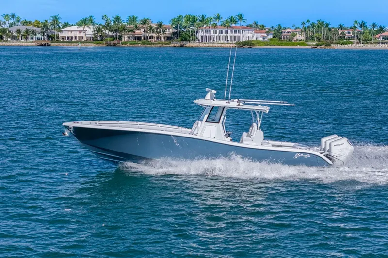 New Stock Yacht Photos Pics 2026 Yellowfin 36 Offshore boat cruising on blue ocean near luxury waterfront homes.