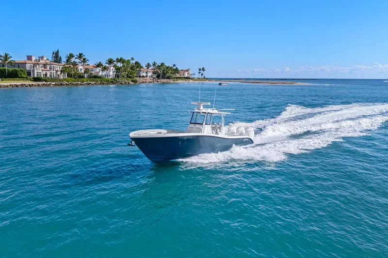 New Stock Yacht Photos Pics 2026 Yellowfin 36 Offshore boat cruising on clear blue water near a coastal area.