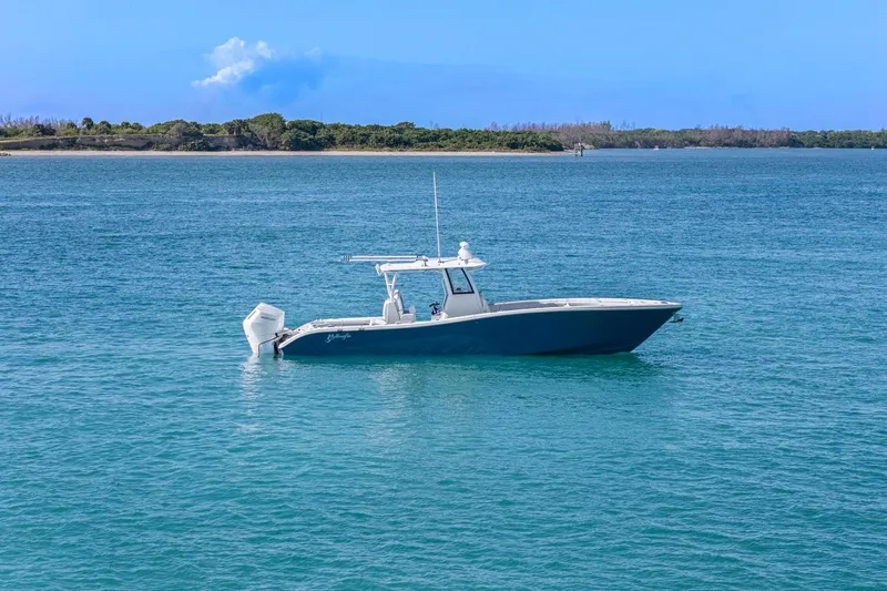 New Stock Yacht Photos Pics 2026 Yellowfin 36 Offshore boat on calm blue water near a scenic shoreline.