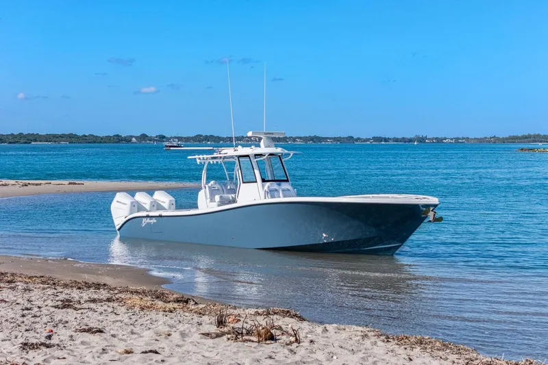 New Stock Yacht Photos Pics 2026 Yellowfin 36 Offshore boat on sandy shore with blue ocean backdrop.