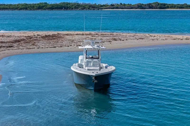 New Stock Yacht Photos Pics 2026 Yellowfin 36 Offshore boat anchored near a sandy beach with clear blue water.