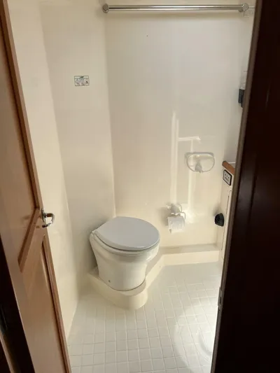 Yacht Z Yacht Photos Pics Compact bathroom in a 1998 Riviera 48 Convertible yacht, featuring a toilet and tiled floor.