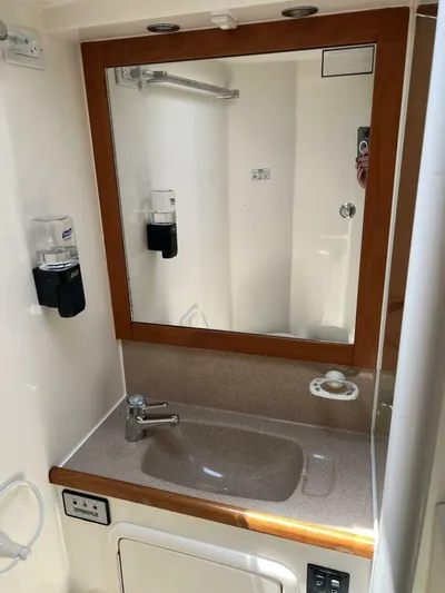 Yacht Z Yacht Photos Pics Bathroom sink area in a 1998 Riviera 48 Convertible yacht, featuring a mirror and soap dispensers.