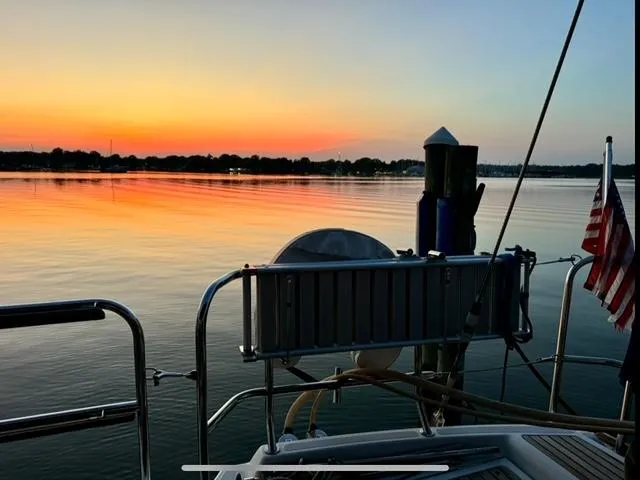 Padraigin II Yacht Photos Pics Jeanneau 58 sailboat at sunset, calm waters, American flag, 2016 model.