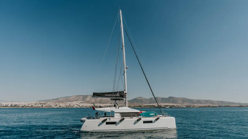  Yacht Photos Pics 2020 Lagoon 52 catamaran sailing on calm waters with mountainous backdrop.