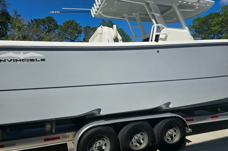 Humble Beginnings Yacht Photos Pics 2022 Invincible 33 Catamaran on trailer, side view with clear blue sky background.