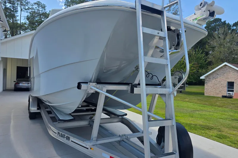 Humble Beginnings Yacht Photos Pics 2022 Invincible 33 Catamaran on trailer, parked in driveway near house.