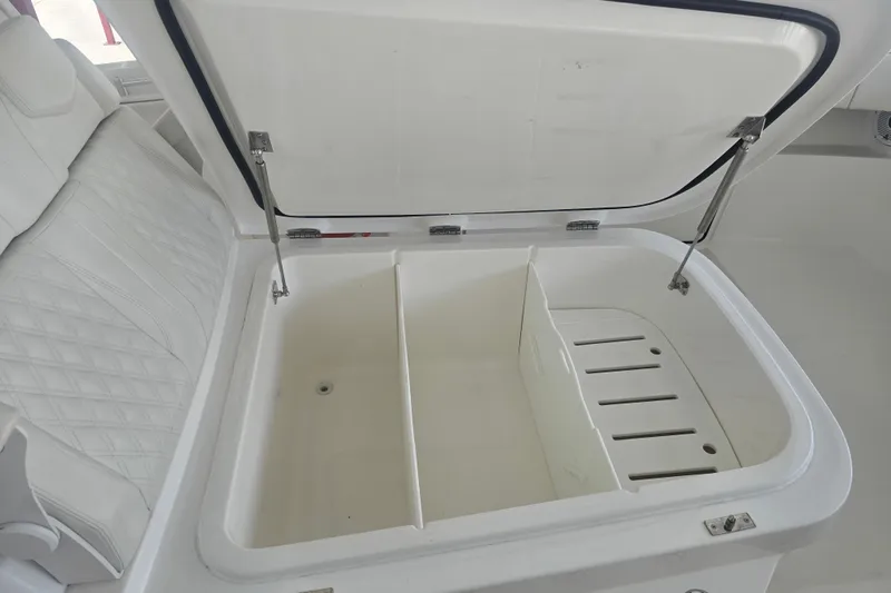 Humble Beginnings Yacht Photos Pics Open storage compartment on 2022 Invincible 33 Catamaran with white cushioned seating.