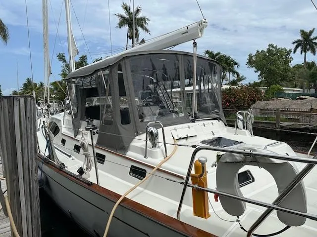 Last Love Yacht Photos Pics Sailboat docked, 2014 Passport 545 Vista, with canopy and lifebuoy, surrounded by palm trees.