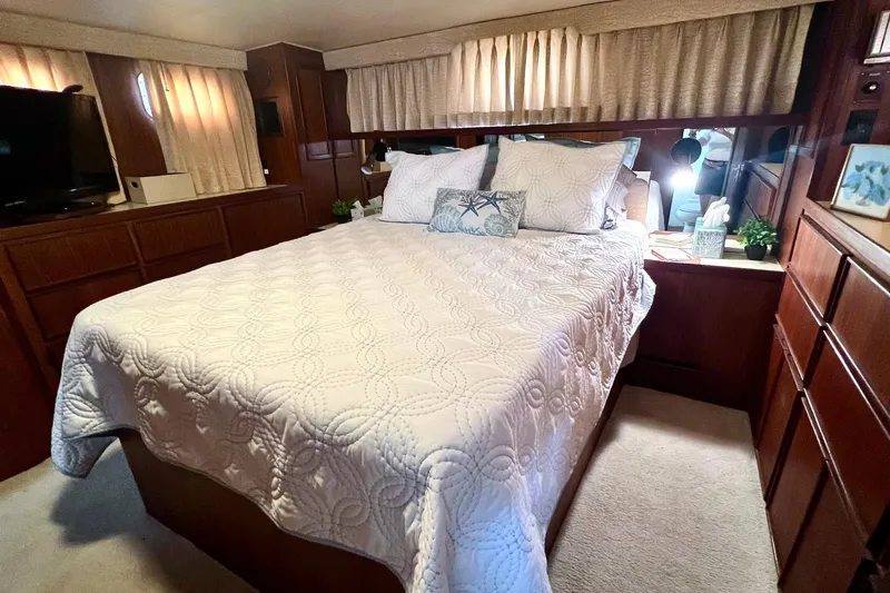 Shangri La Yacht Photos Pics Luxurious bedroom interior of 1988 Hatteras 43 Motor Yacht with elegant bedding and wood cabinetry.