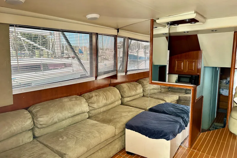  Yacht Photos Pics Interior of a 1989 Viking 48 yacht with beige sofa, wood paneling, and large windows.