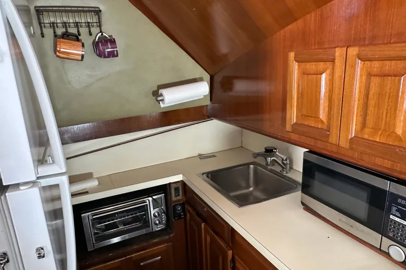  Yacht Photos Pics Compact kitchen in a 1989 Viking 48 boat with wooden cabinets, sink, and appliances.