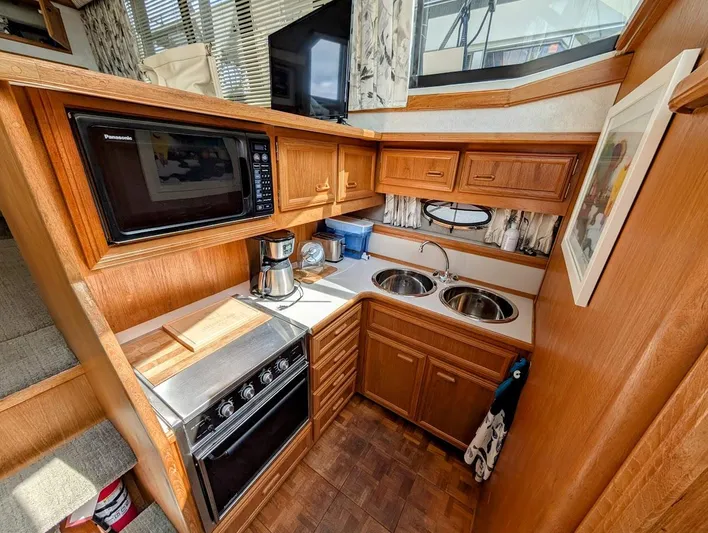 Infinity Bound Yacht Photos Pics 1991 Carver 430 Cockpit Motor Yacht kitchen with wood cabinetry, microwave, stove, and dual sinks.