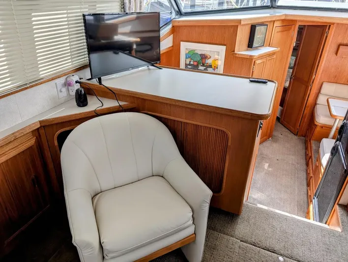 Infinity Bound Yacht Photos Pics Interior of 1991 Carver 430 Cockpit Motor Yacht with chair, TV, and wooden cabinetry.