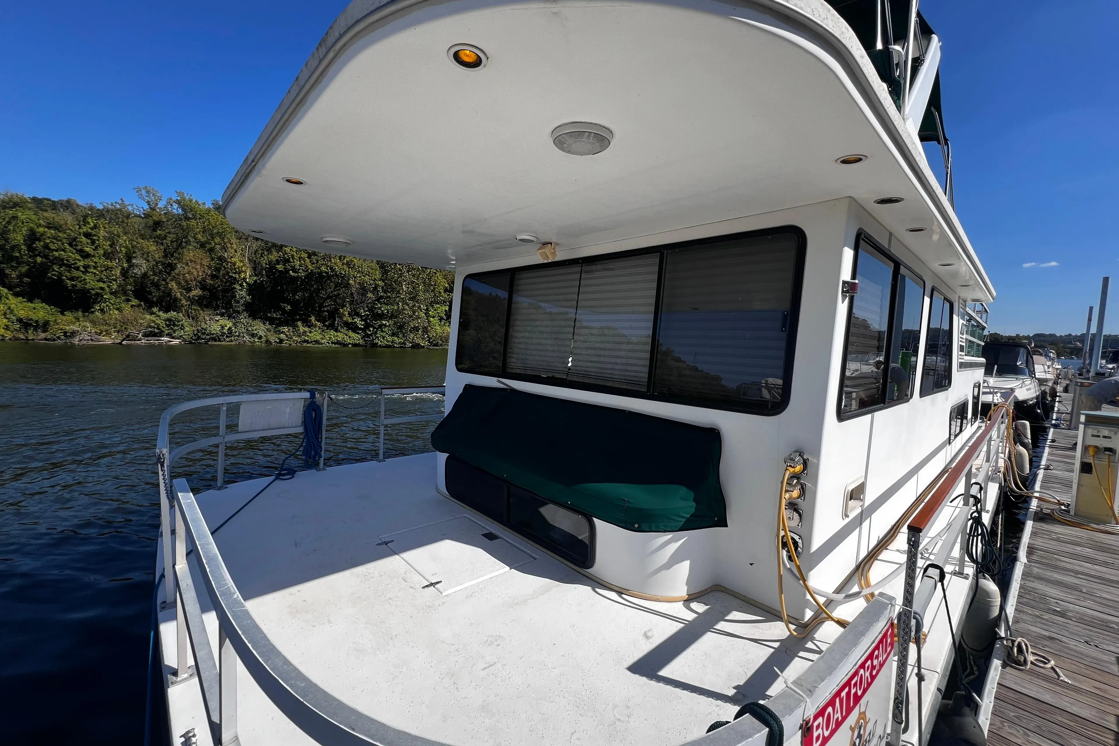 1994 Gibson 44 Classic houseboat docked by a scenic river under a clear blue sky.