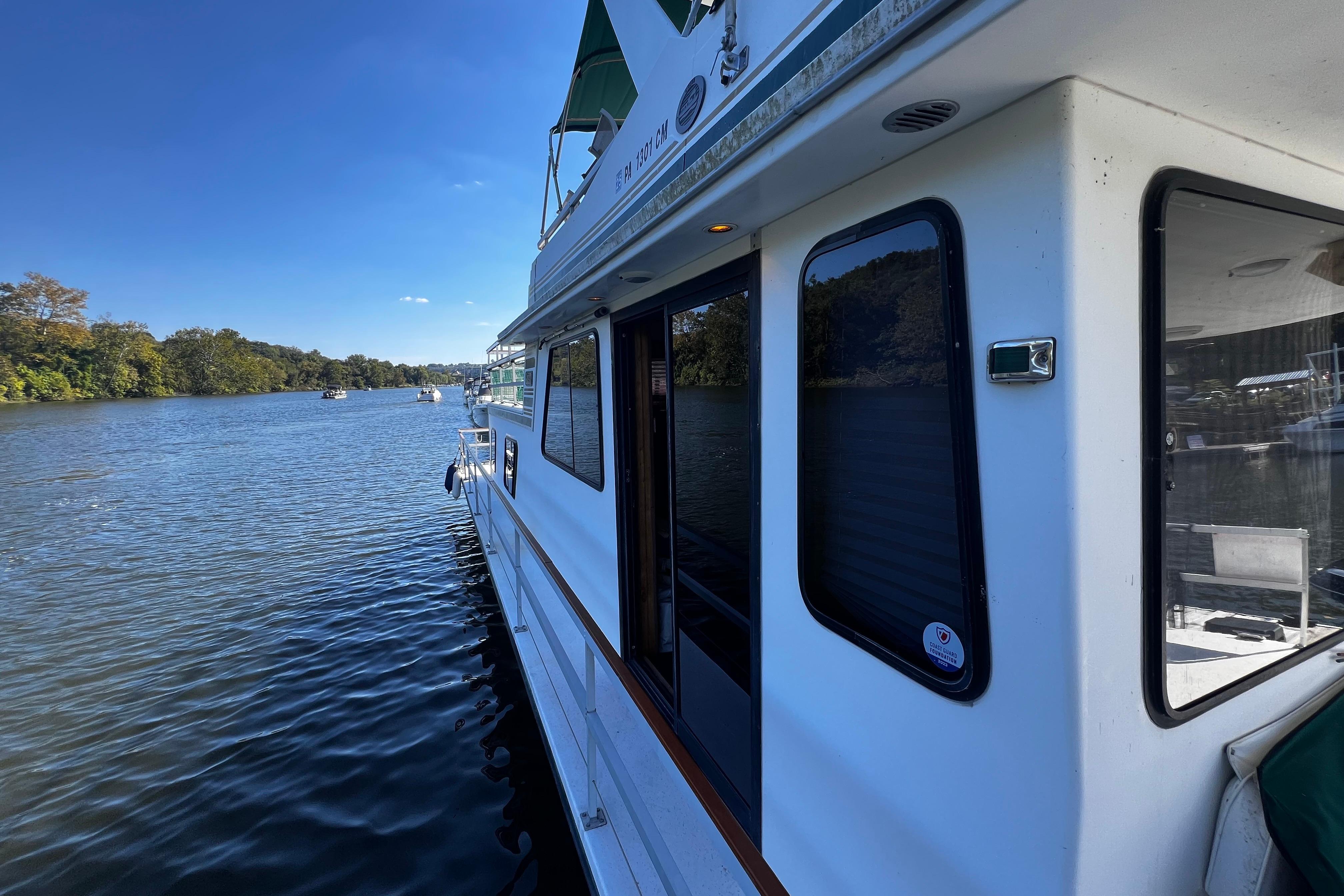 1994 Gibson 44 Classic houseboat on a serene river under a clear blue sky.