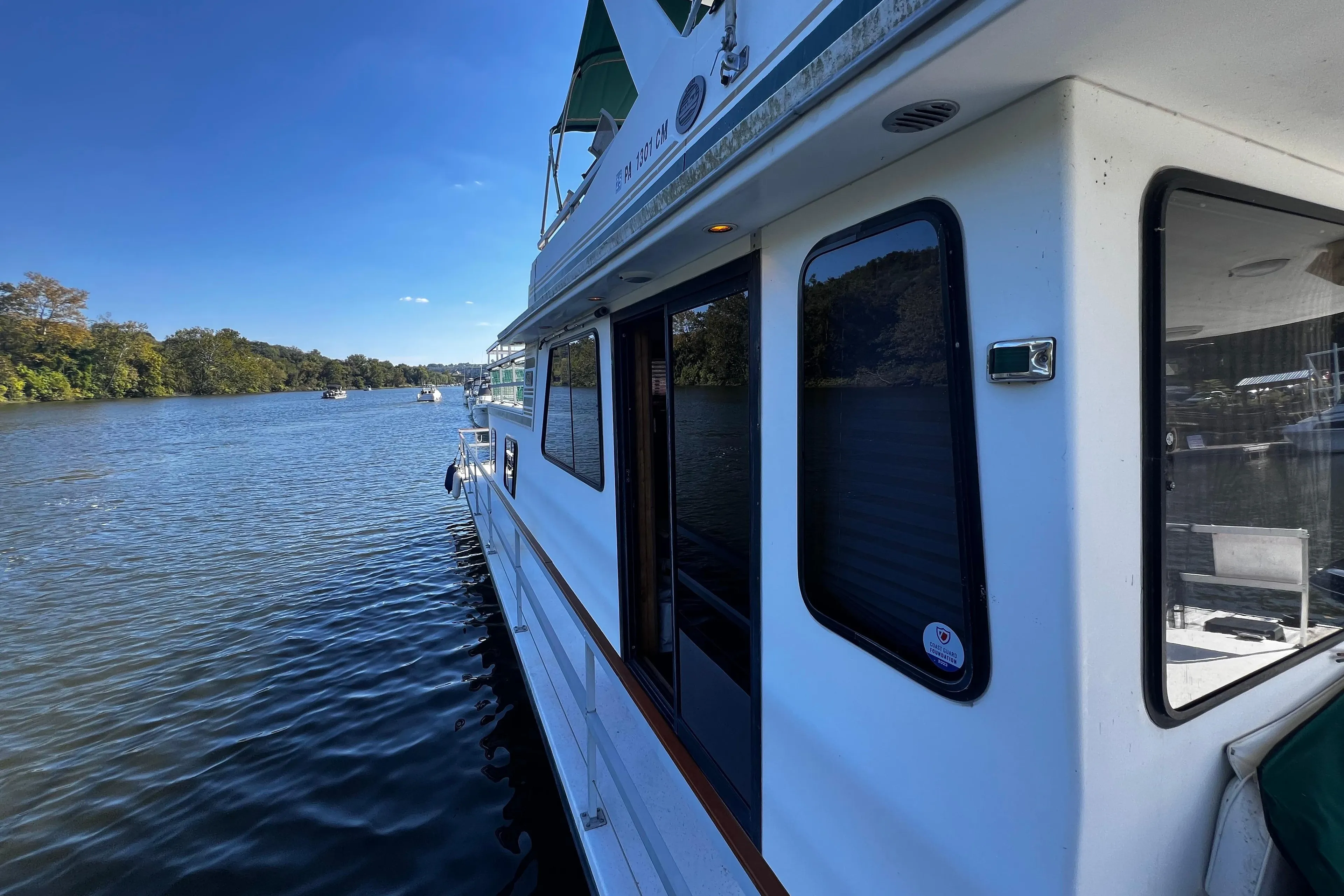 1994 Gibson 44 Classic houseboat on a serene river under a clear blue sky.