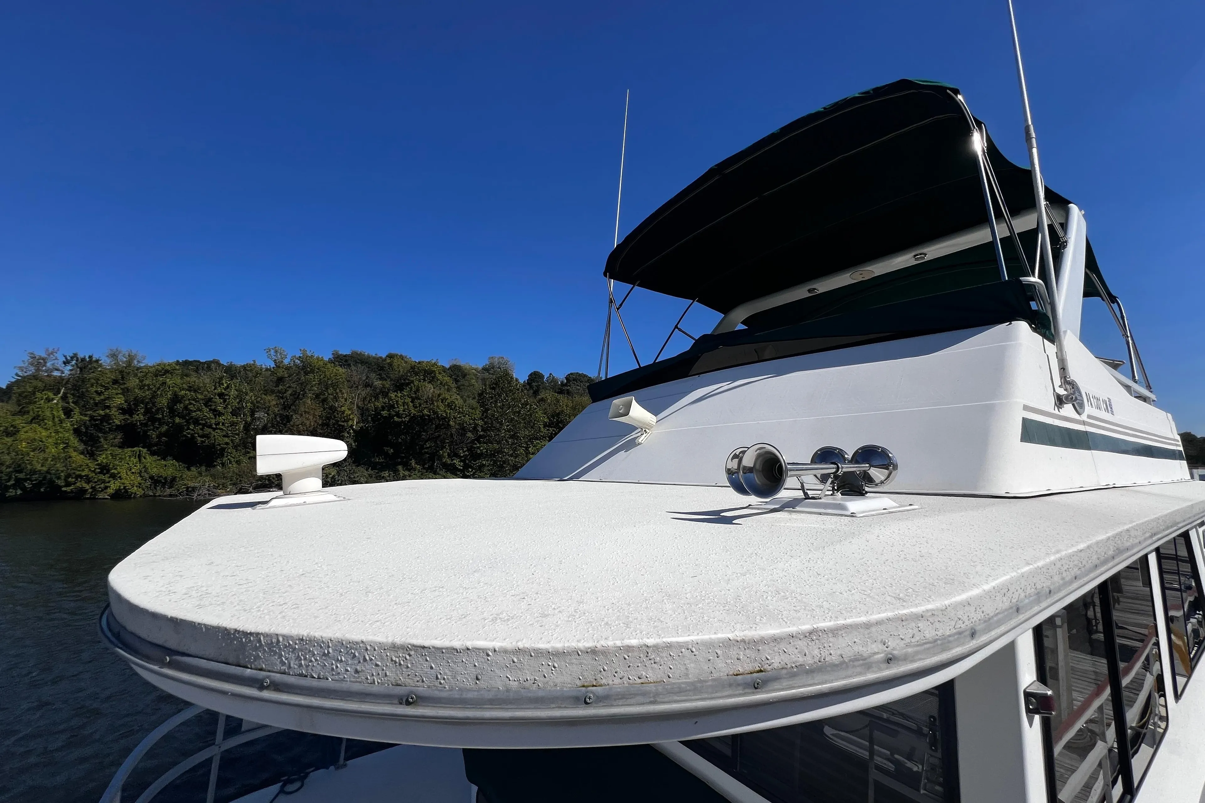 1994 Gibson 44 Classic boat on water, clear sky, lush green shoreline.