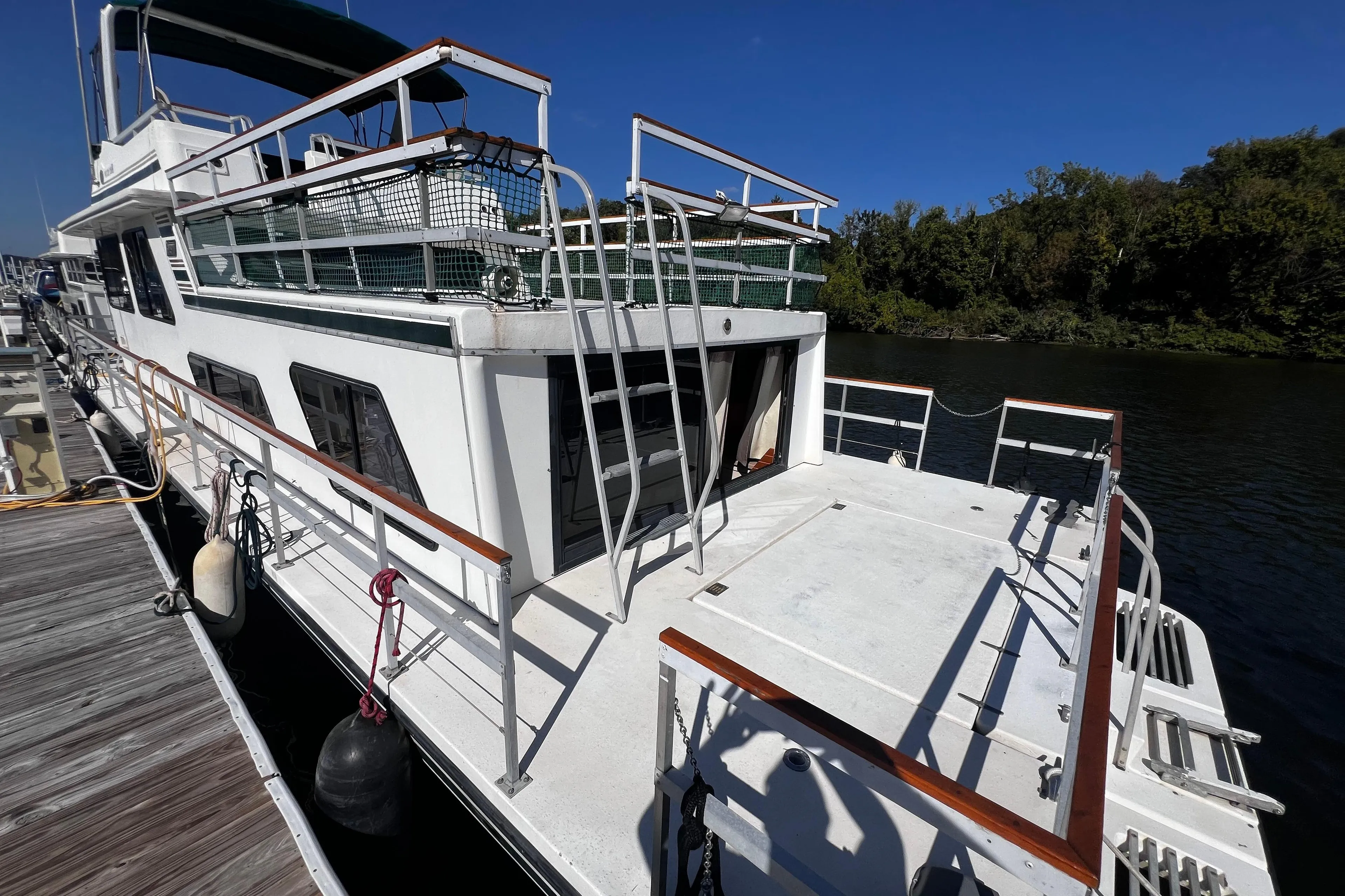 1994 Gibson 44 Classic houseboat docked on a sunny day, surrounded by water and trees.