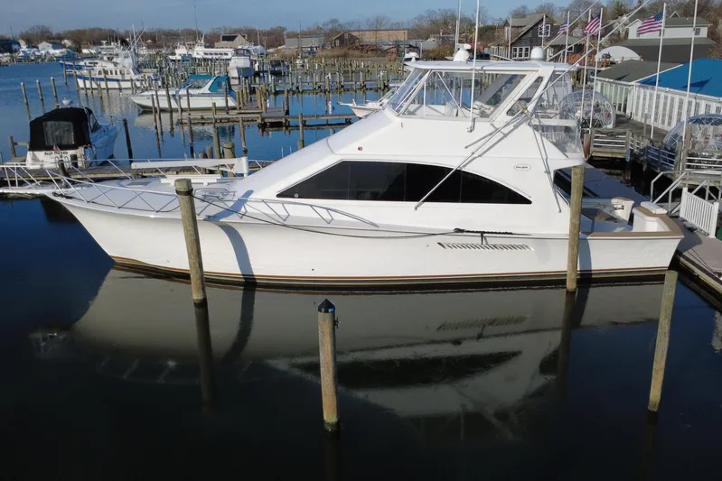 The Oar Deal Yacht Photos Pics 1999 Ocean Yachts 56 Super Sport docked at a marina, reflecting on calm water.