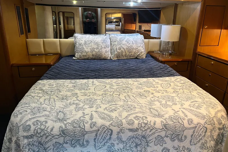 The Oar Deal Yacht Photos Pics Luxurious bedroom interior of 1999 Ocean Yachts 56 Super Sport, featuring elegant bedding and wood cabinetry.