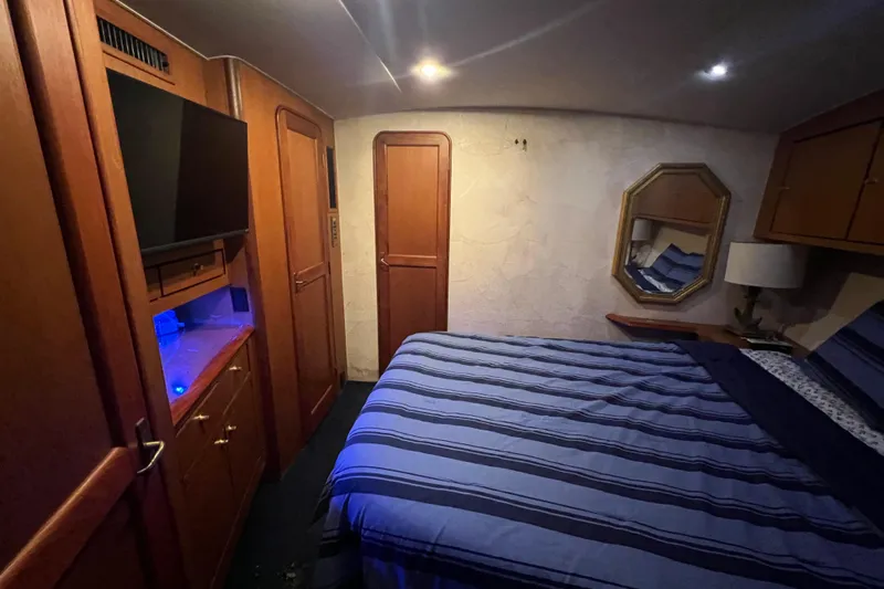 The Oar Deal Yacht Photos Pics Luxurious bedroom interior of 1999 Ocean Yachts 56 Super Sport with striped bedding and wooden cabinetry.