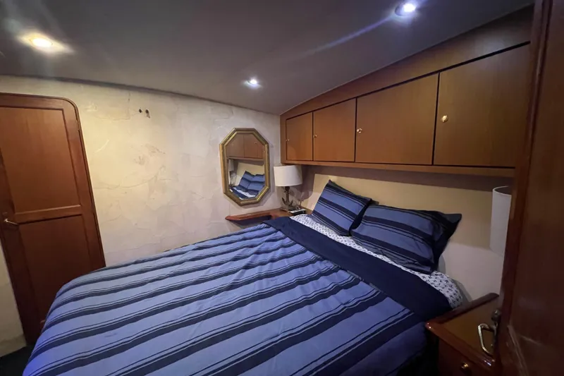 The Oar Deal Yacht Photos Pics Bedroom interior of 1999 Ocean Yachts 56 Super Sport with striped bedding and wooden cabinets.