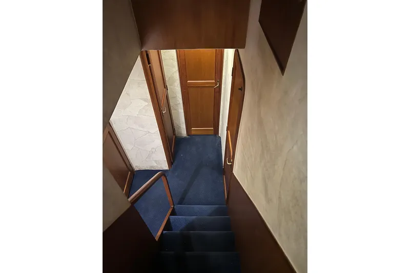 The Oar Deal Yacht Photos Pics Stairway inside 1999 Ocean Yachts 56 Super Sport, featuring wooden doors and blue carpet.