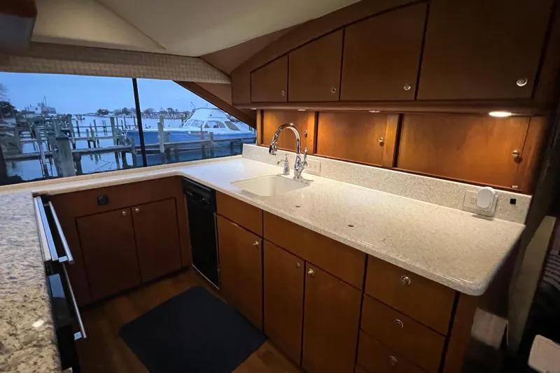 The Oar Deal Yacht Photos Pics Luxurious kitchen interior of 1999 Ocean Yachts 56 Super Sport with wooden cabinets and marina view.
