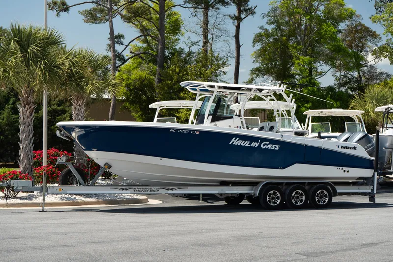  Yacht Photos Pics 2018 Wellcraft 302 Fisherman boat on trailer, parked outdoors with trees in background.