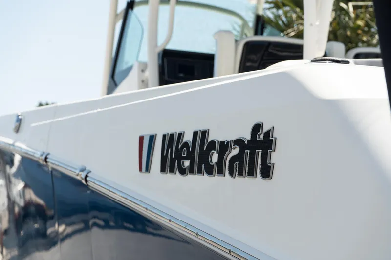  Yacht Photos Pics 2018 Wellcraft 302 Fisherman boat, close-up of logo on white and blue hull.