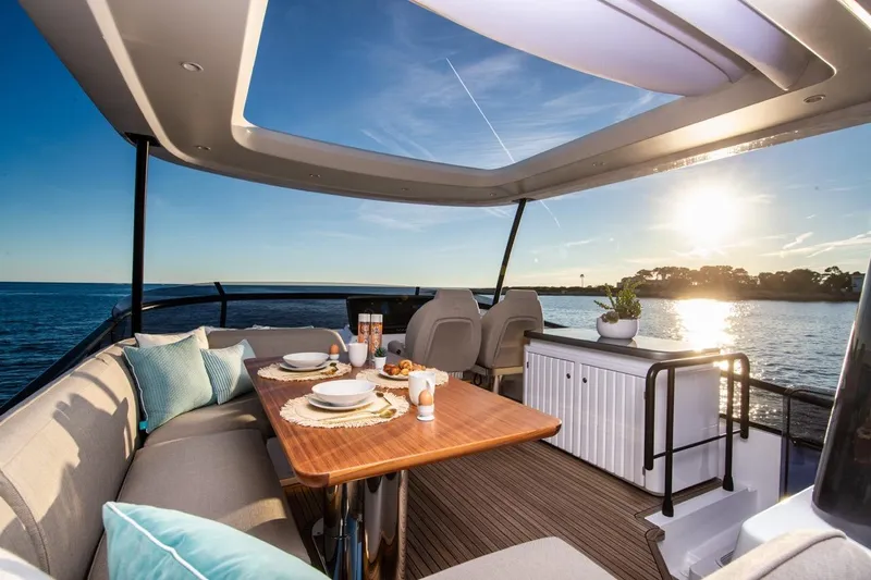  Yacht Photos Pics Luxurious 2025 Azimut Magellano 60 yacht deck with elegant dining setup at sunset.